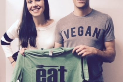 Man and women holding eat more plants shirt