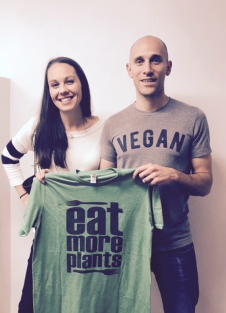 Man and women holding eat more plants shirt